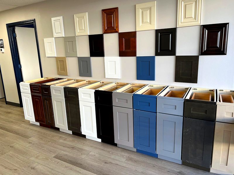 Showroom sample wall: checkerboard of door samples (antique white raised-panel, cherry — on display at MNK Cabinet's Norcross, GA showroom
