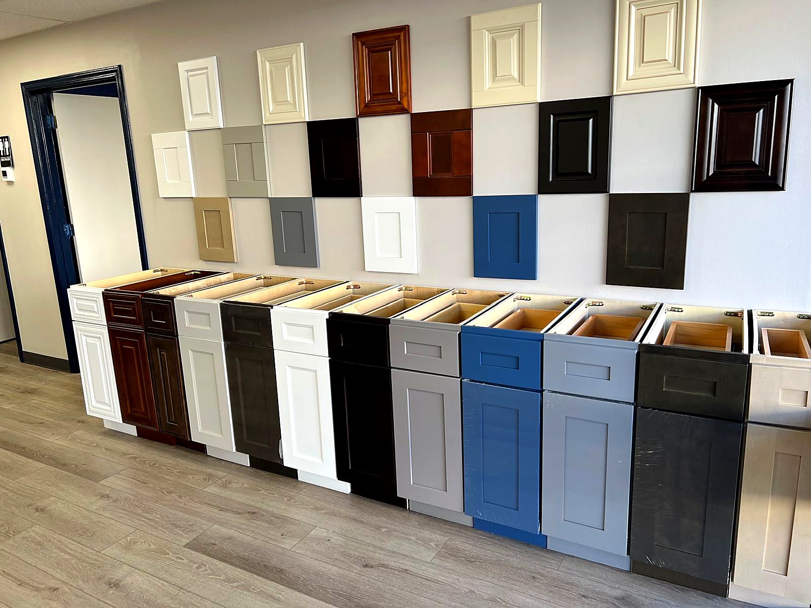 Wall of cabinet door styles and factory finish color samples at the MNK Cabinet showroom in Norcross, GA