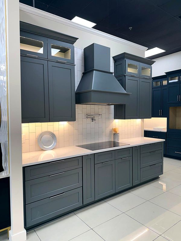 Charcoal gray shaker kitchen with charcoal wood range hood, lighted glass-top uppers — kitchen by MNK Cabinet in metro Atlanta
