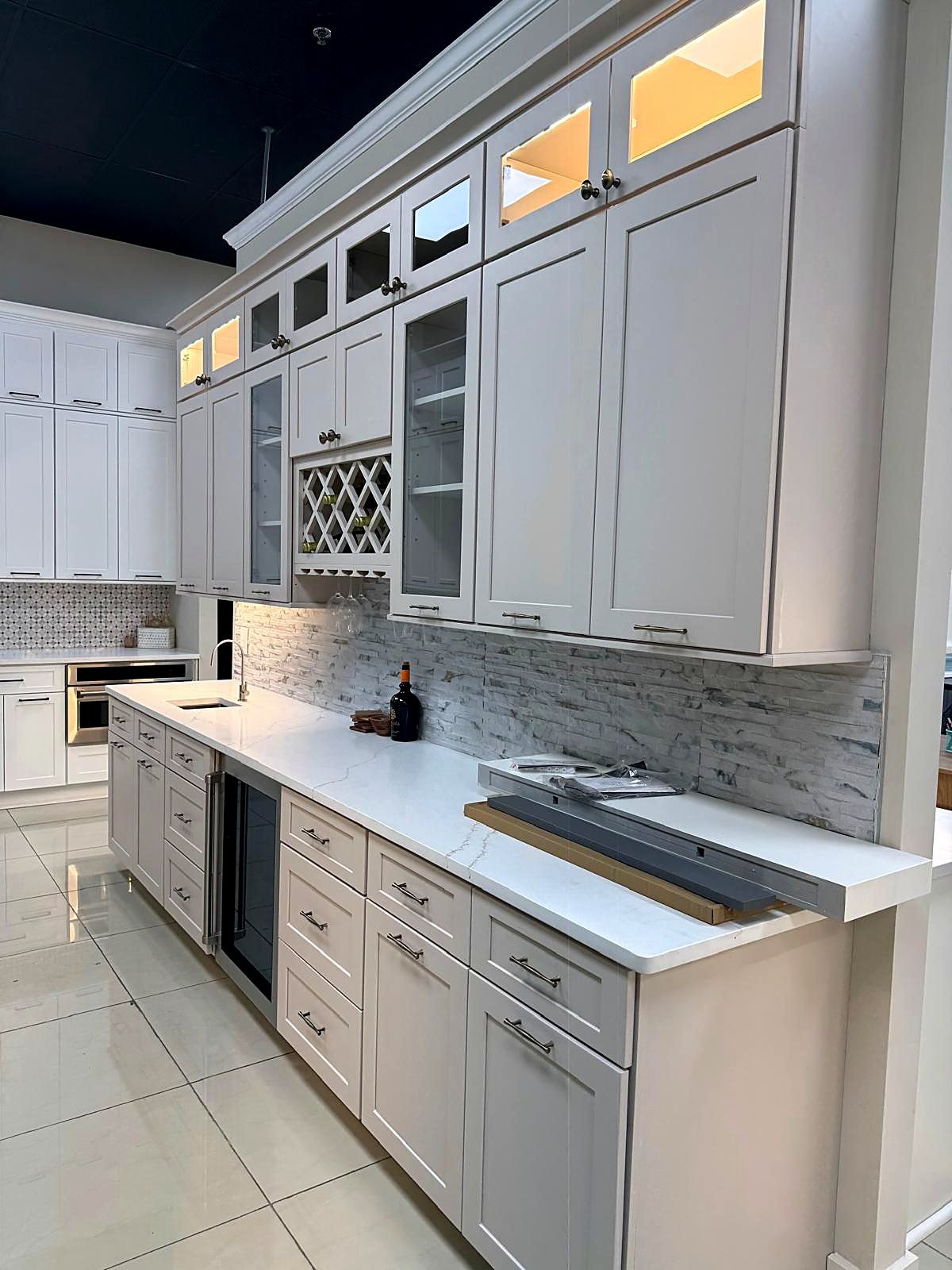 Greige shaker bar wall with open shelving and a wine rack in the MNK Cabinet showroom in Norcross, GA