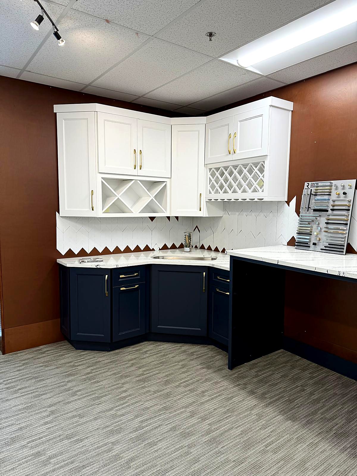 White shaker upper cabinets over navy base cabinets with built-in wine rack storage on display